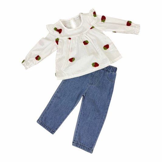 Conjunto Acüchichi para niña con blusa blanca de manga larga, estampado de fresas y volantes, y pantalón jeans azul.