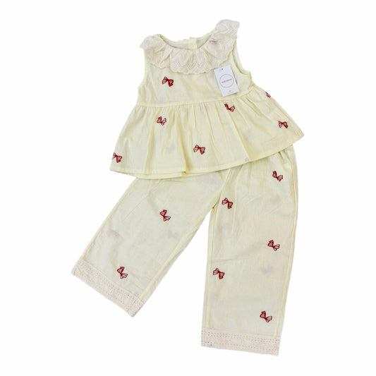 Conjunto Acüchichi de dos piezas amarillo pastel para niñas con encaje en cuello y bajo y estampado de lazos rojos