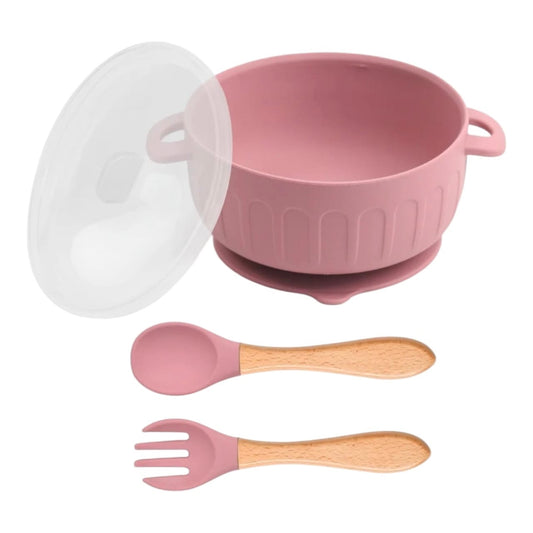 Set de alimentación Acüchichi de silicona rosa con tazón de succión, tapa y cubiertos con mango de madera ergonómico.